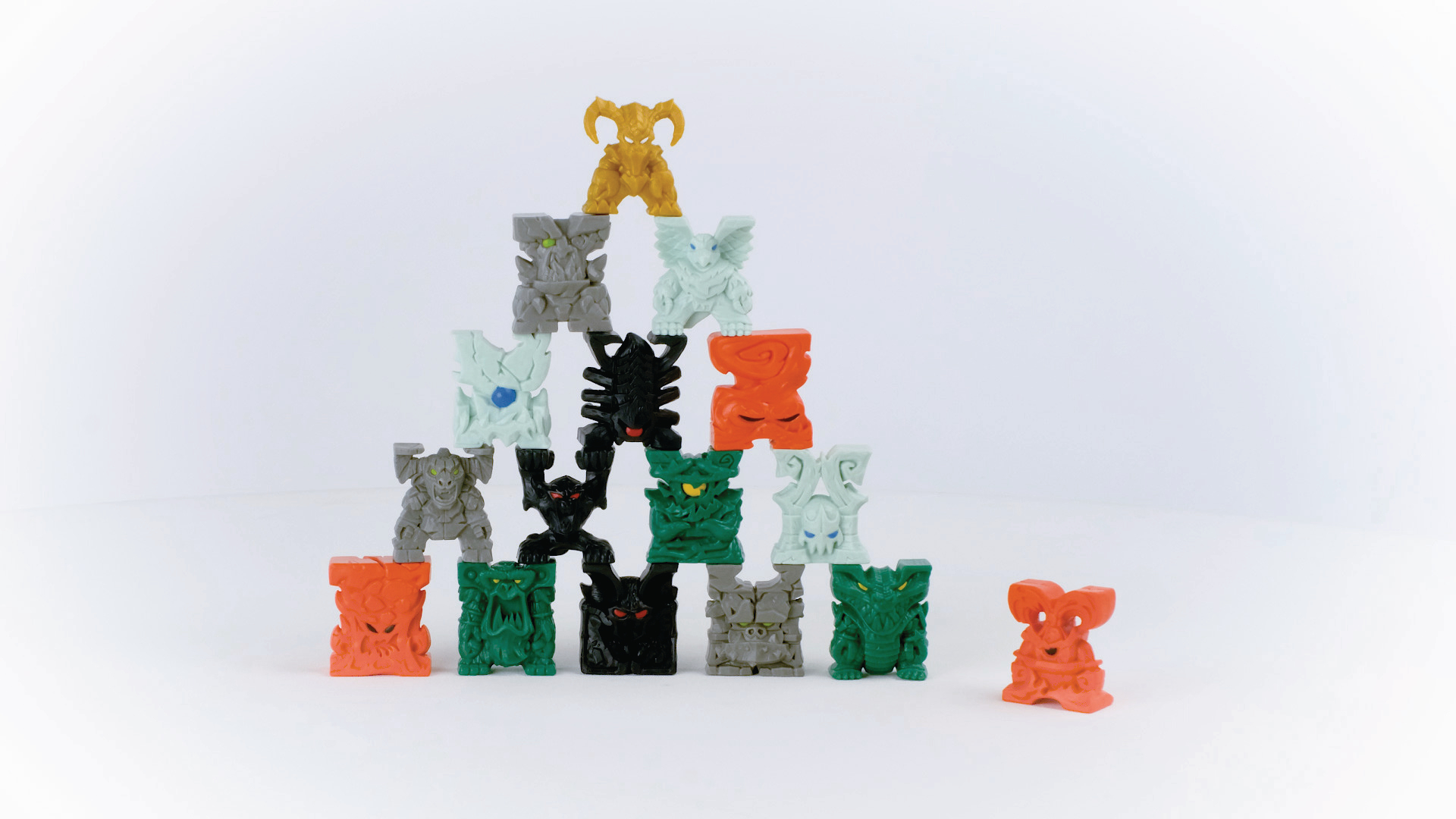 Pyramide aus bunten monsterartigen Spielzeugen, weißer Hintergrund, Studioaufnahme.