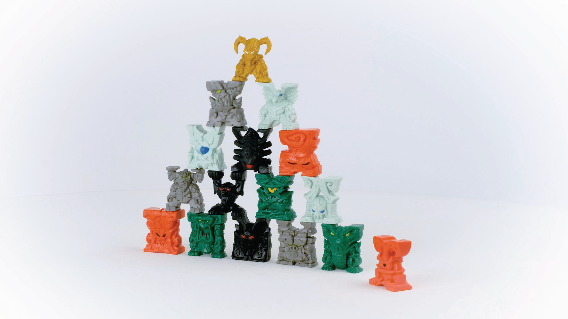 Eine Pyramide aus bunten, abstrakten Spielzeugfiguren in verschiedenen Formen und Farben vor Weiß.