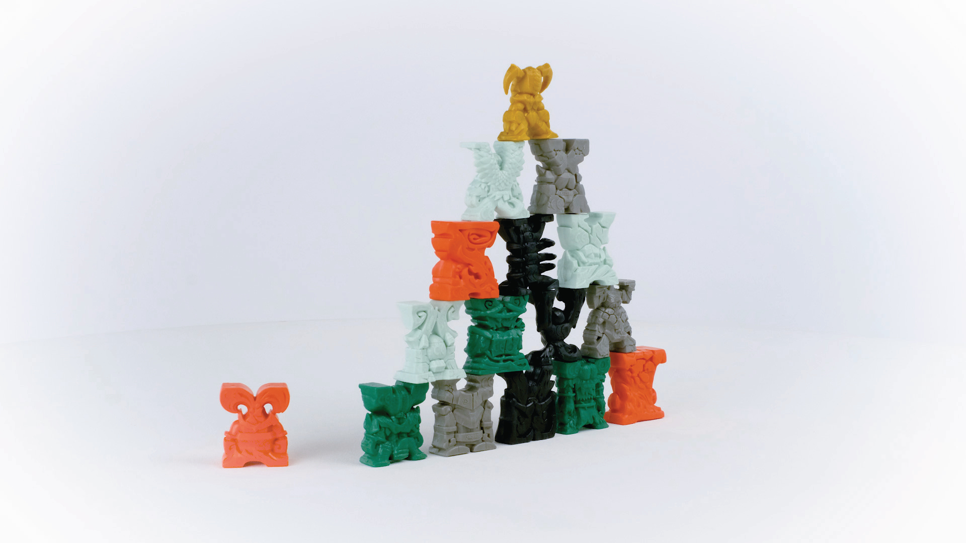 Bunte Holzfiguren pyramidenförmig gestapelt, mit einer einzelnen Figur daneben.