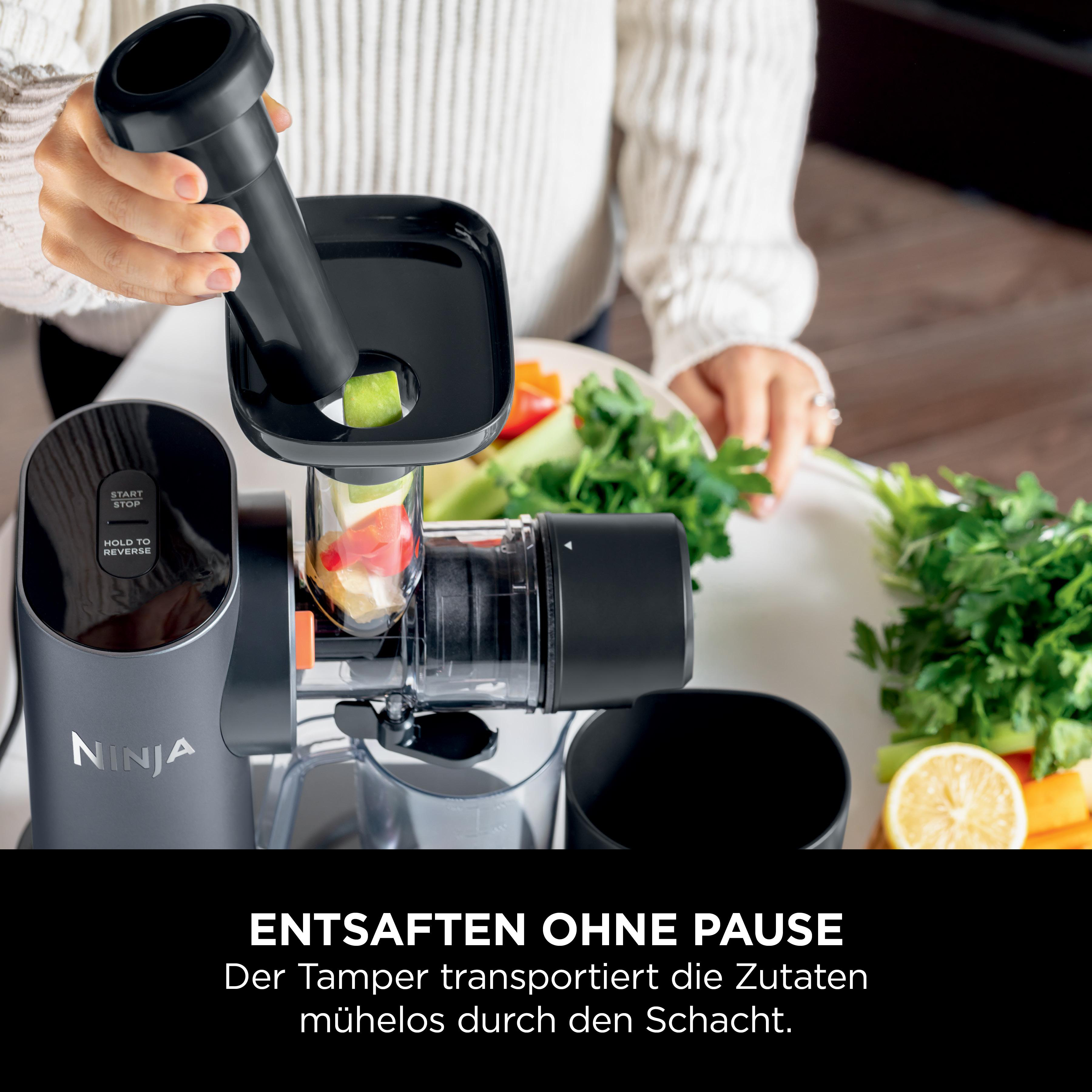 Frau, die Gemüse mit einem Ninja-Gerät entsaftet, eine Zitrone und Sellerie sind sichtbar.