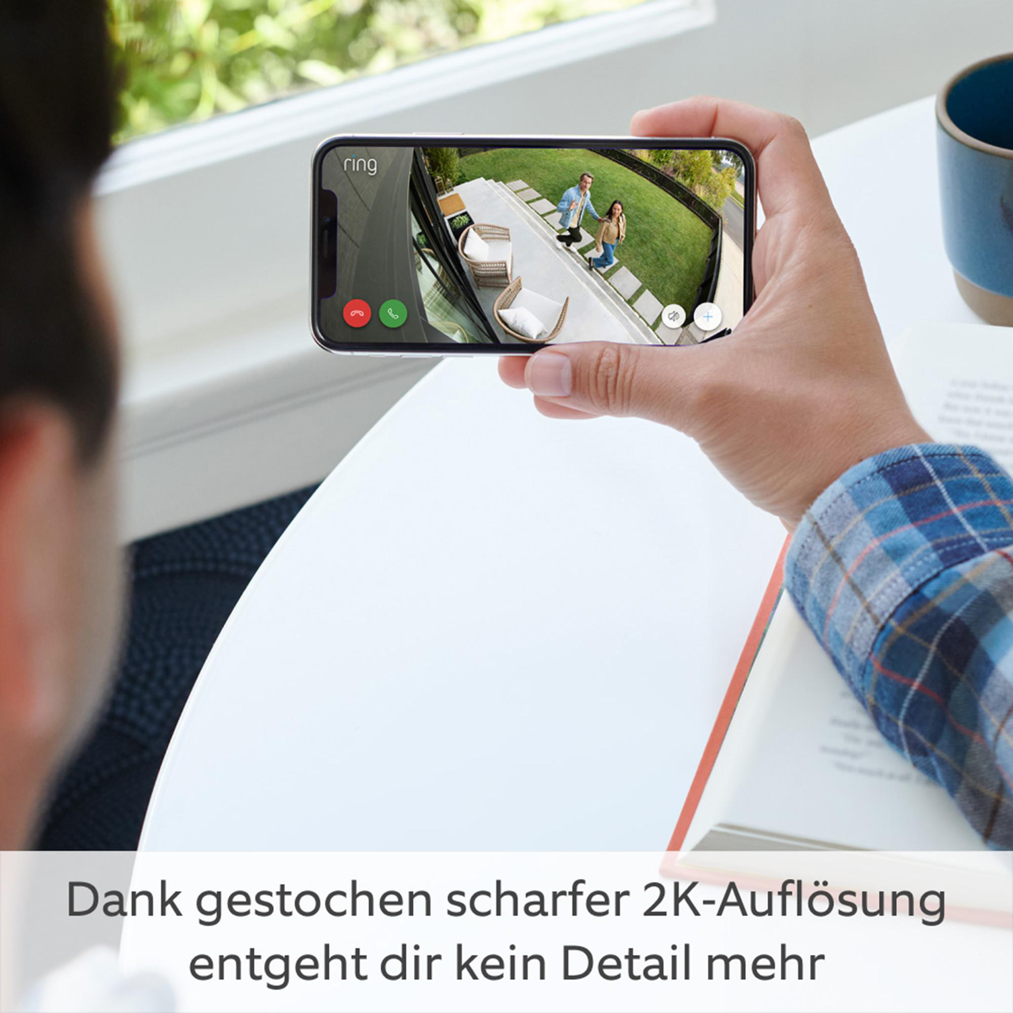 Ein Mann hält ein Telefon, das einen Videoanruf auf einer Veranda zeigt.