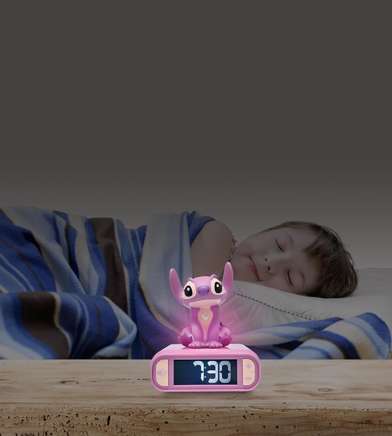 Un niño durmiendo con un despertador de Stitch en una mesa.