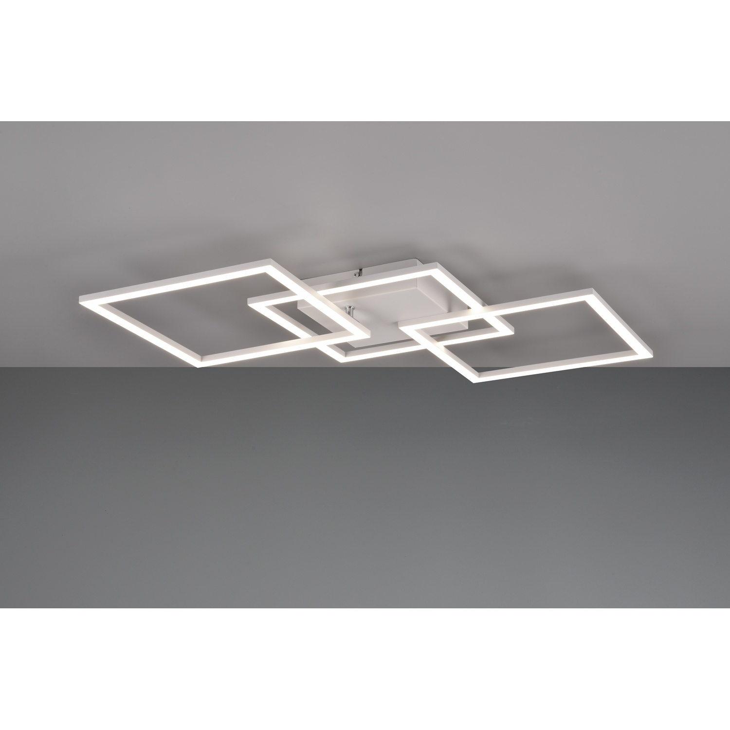 Un apparecchio di illuminazione a soffitto bianco con tre cornici luminose quadrate interconnesse, su un soffitto grigio.