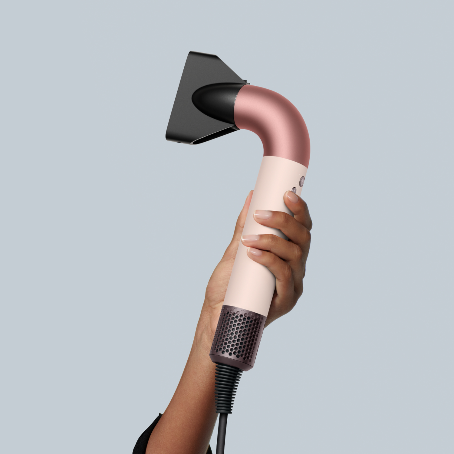 Une personne tenant un sèche-cheveux avec une buse noire et un corps en or rose.