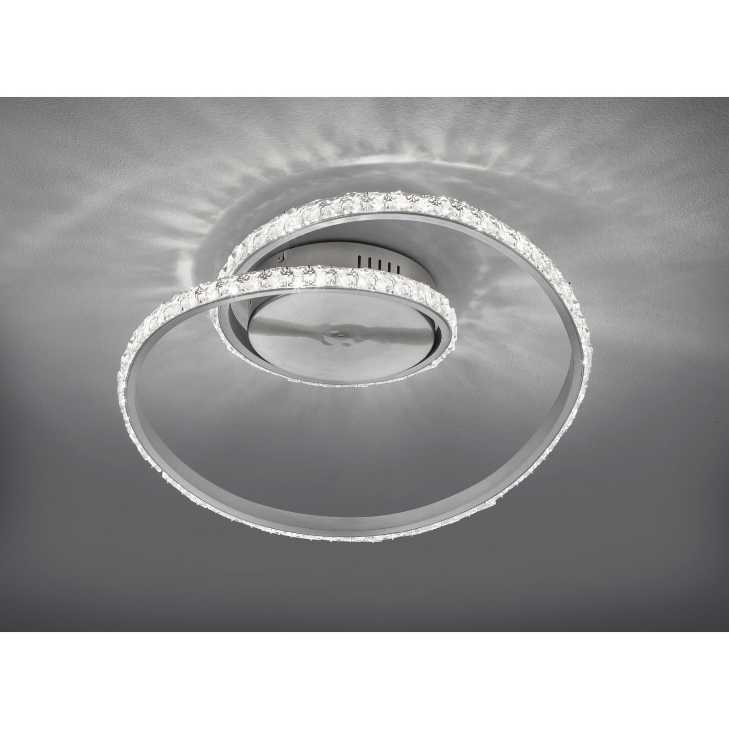 Un moderno lampadario a soffitto con un design a spirale. Ha cristalli e una finitura argentata.