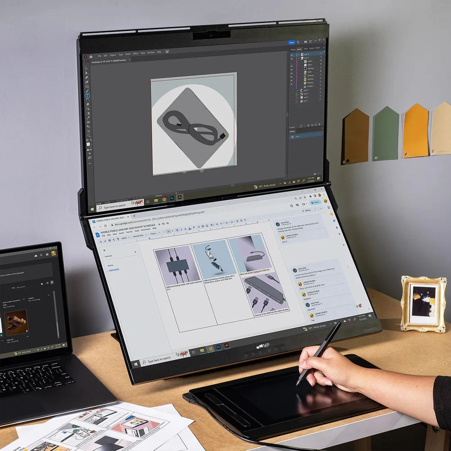 Une personne travaille sur une configuration d'écran double avec un ordinateur portable, un stylo et une tablette graphique sur un bureau.