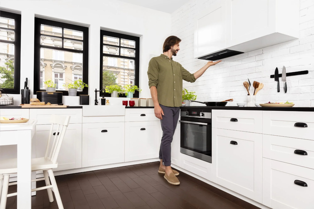 Mężczyzna w kuchni, wskazujący na okap kuchenny.