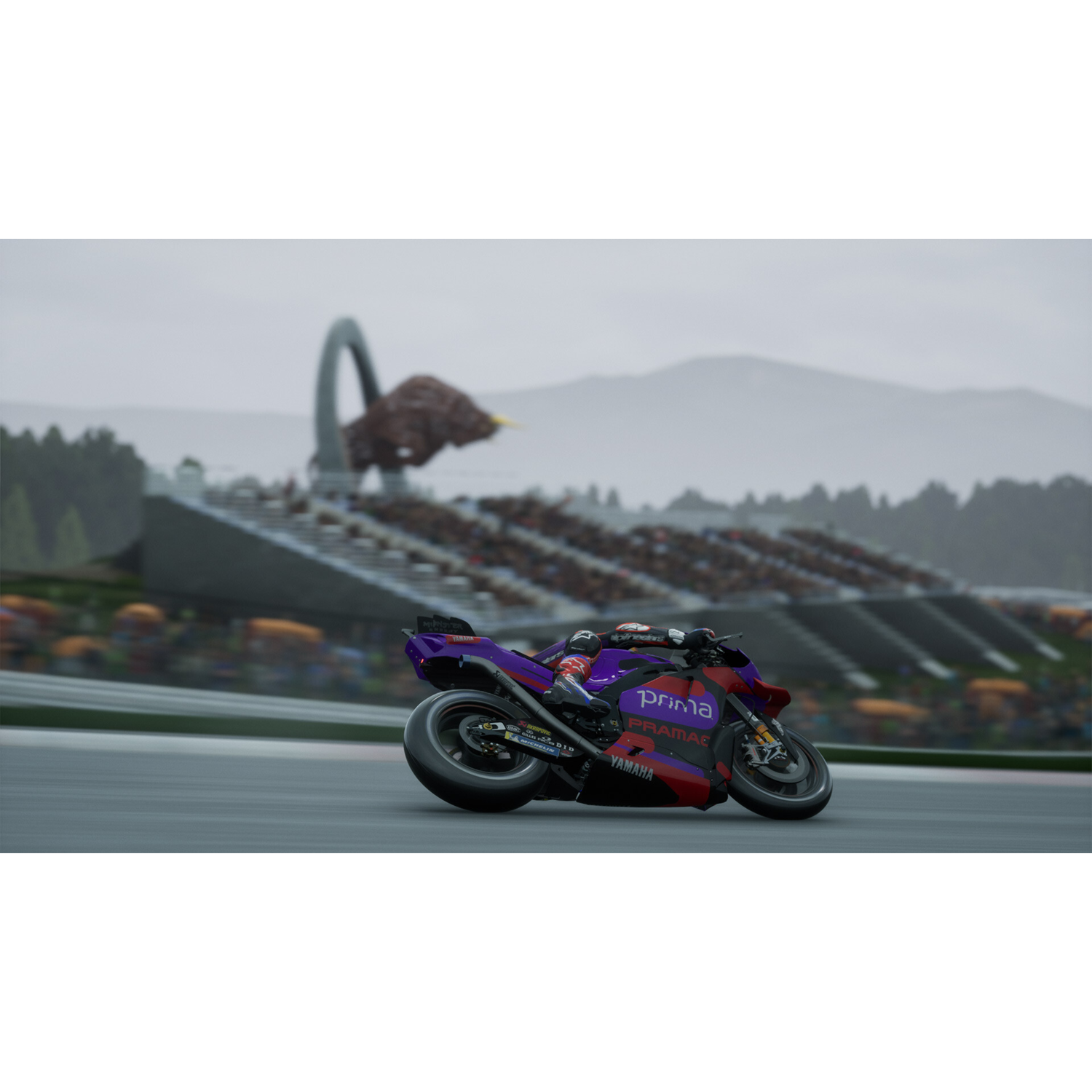 A motorcycle racing on a track, with a stadium in the background and cloudy sky.