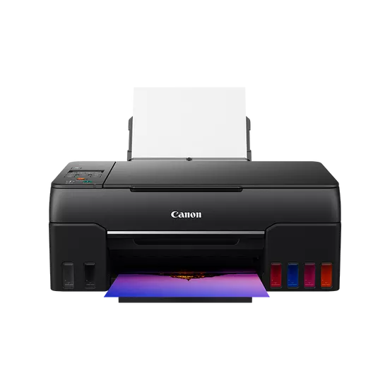 Se muestra una impresora Canon negra. Tiene una bandeja de papel blanca y una imagen en color impresa en la bandeja de salida. Fondo negro.