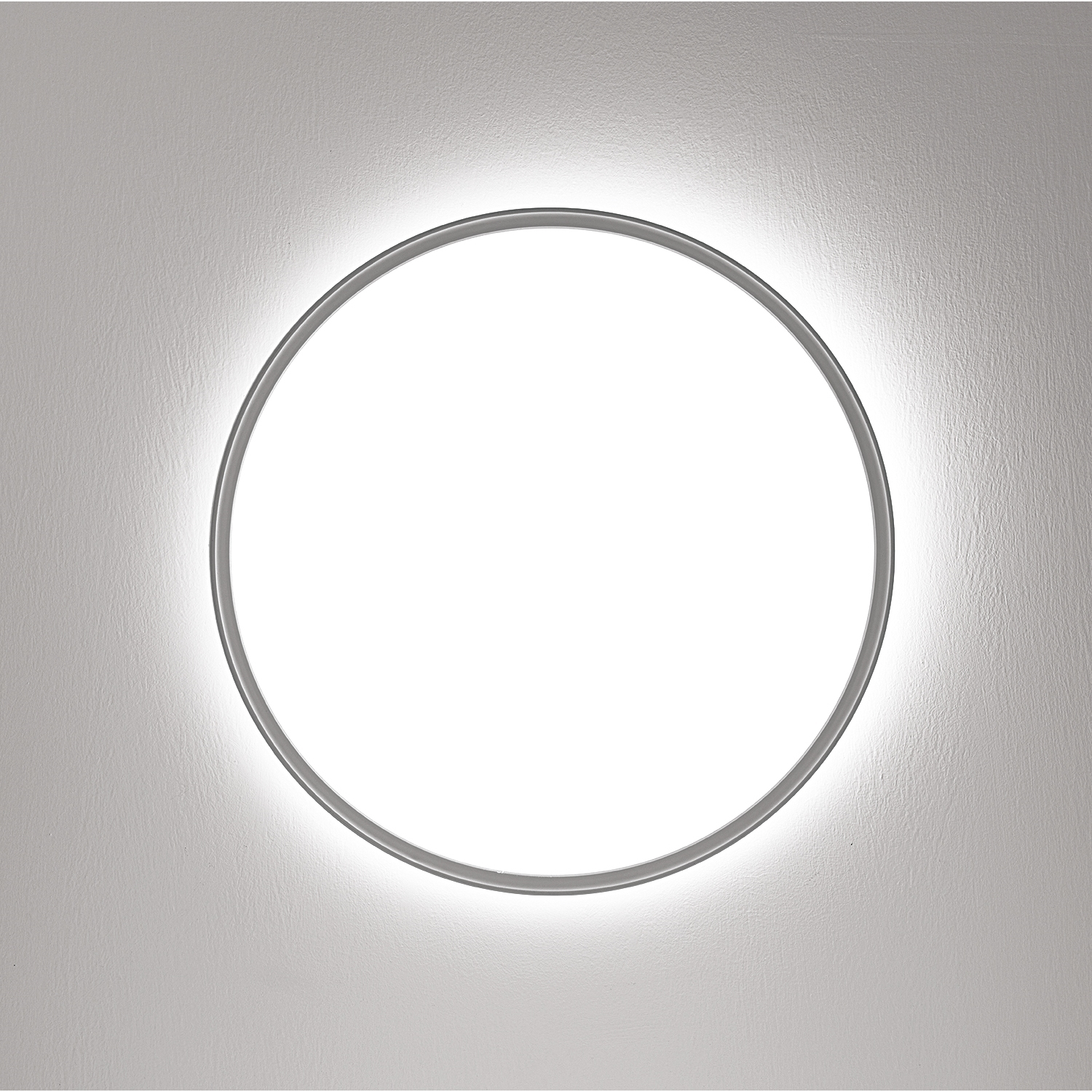 Una luce ad anello argentata su un muro grigio strutturato, che emette un bagliore brillante.