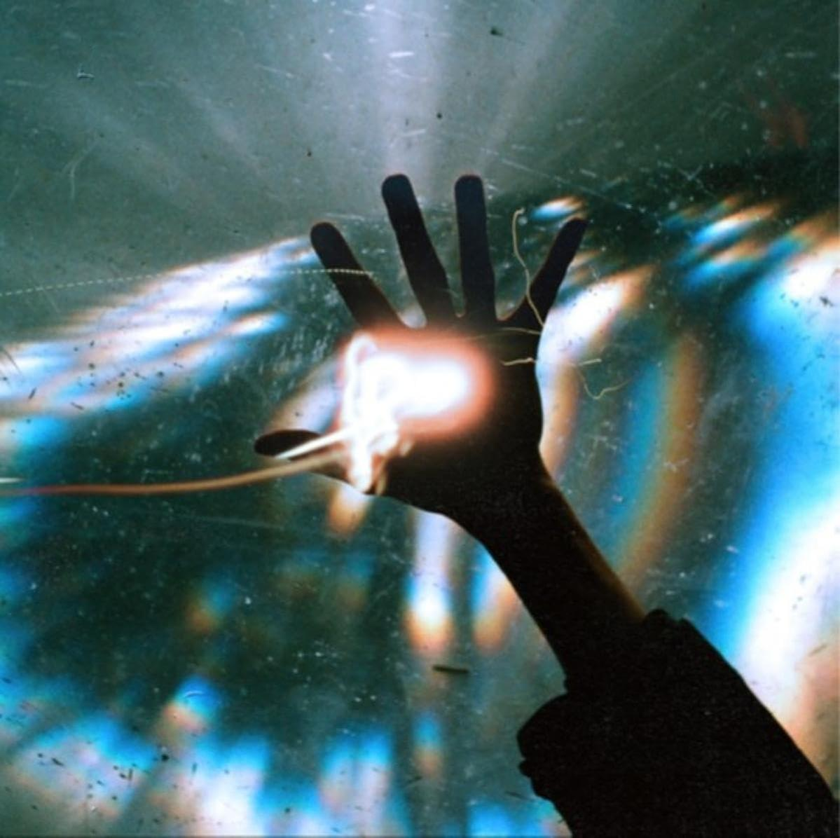 Eine Hand im Schatten vor hellem Licht mit Strahlen. Die Hand ist der Hauptfokus.