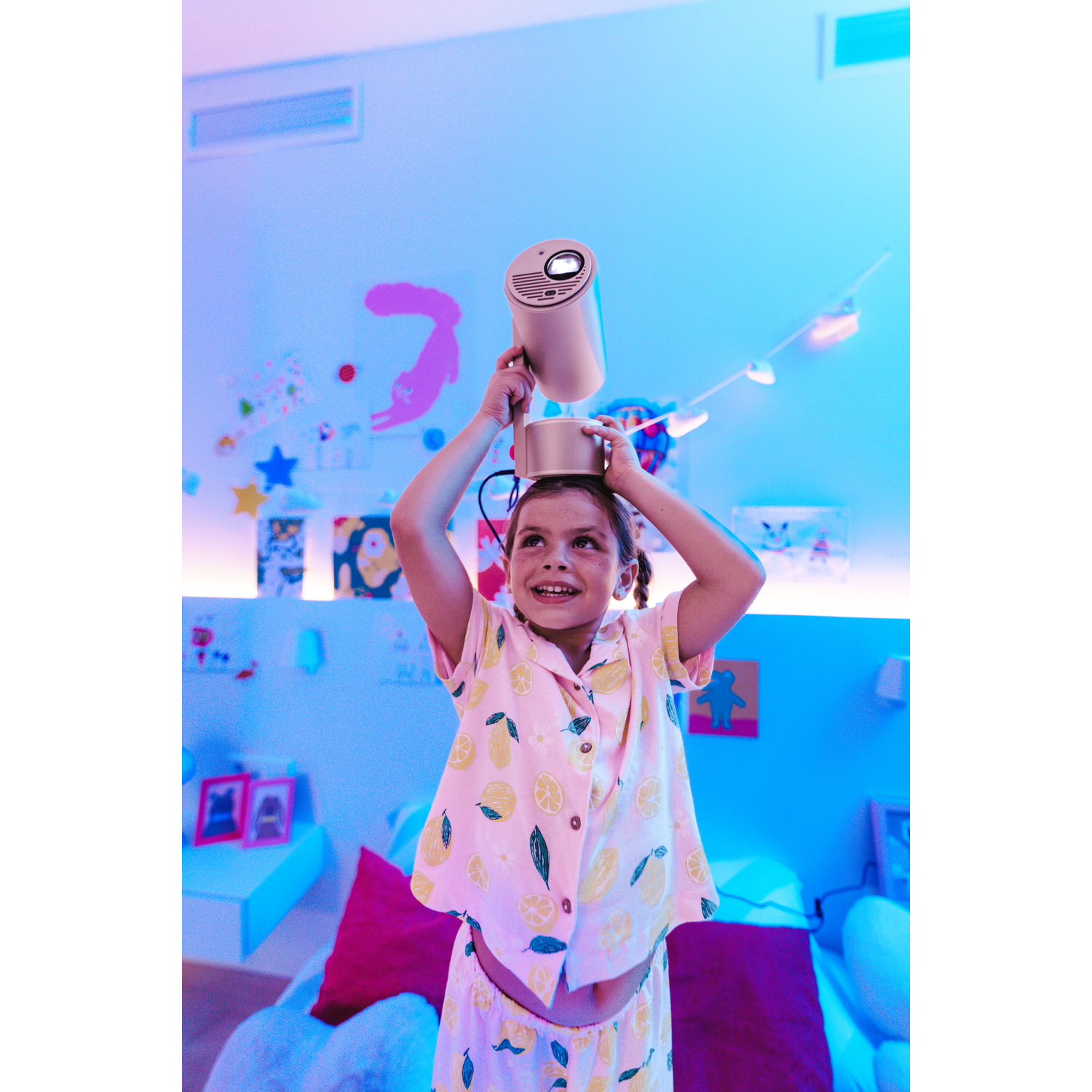 Une jeune fille en pyjama tient un projecteur sur sa tête.