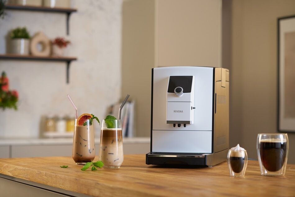 Biały ekspres do kawy z dwoma napojami mrożonymi na drewnianej powierzchni.