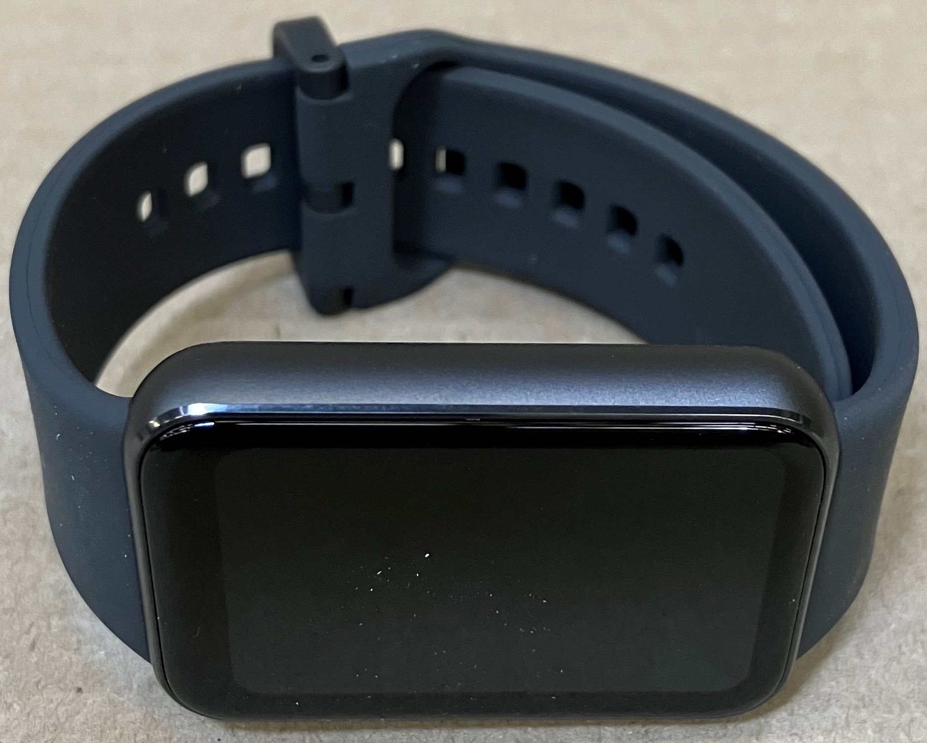 Niebieski smartwatch z ciemnym ekranem i niebieskim paskiem.