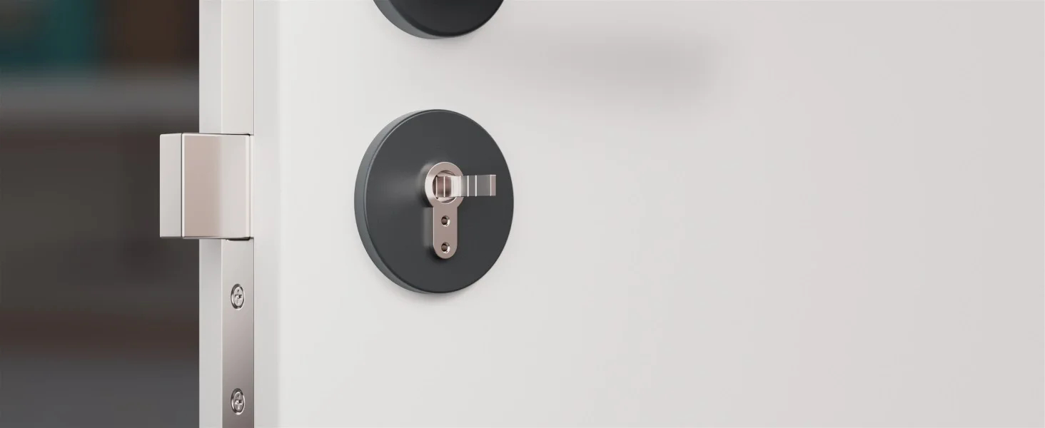 Zbliżenie zamka do drzwi na białych drzwiach. Zamek jest ciemnoszary, a rama srebrna.