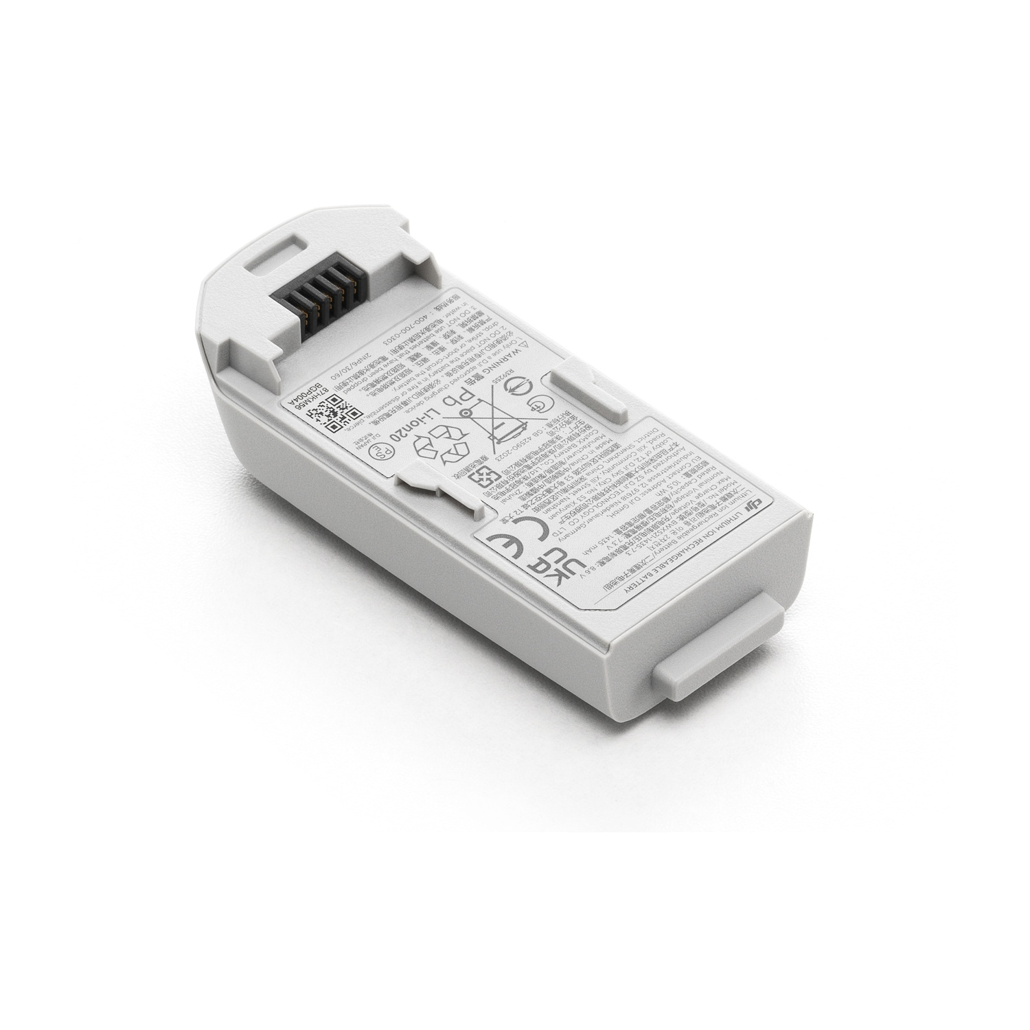 Una batteria per droni grigio chiaro su una superficie bianca, con etichette e una porta di ricarica.