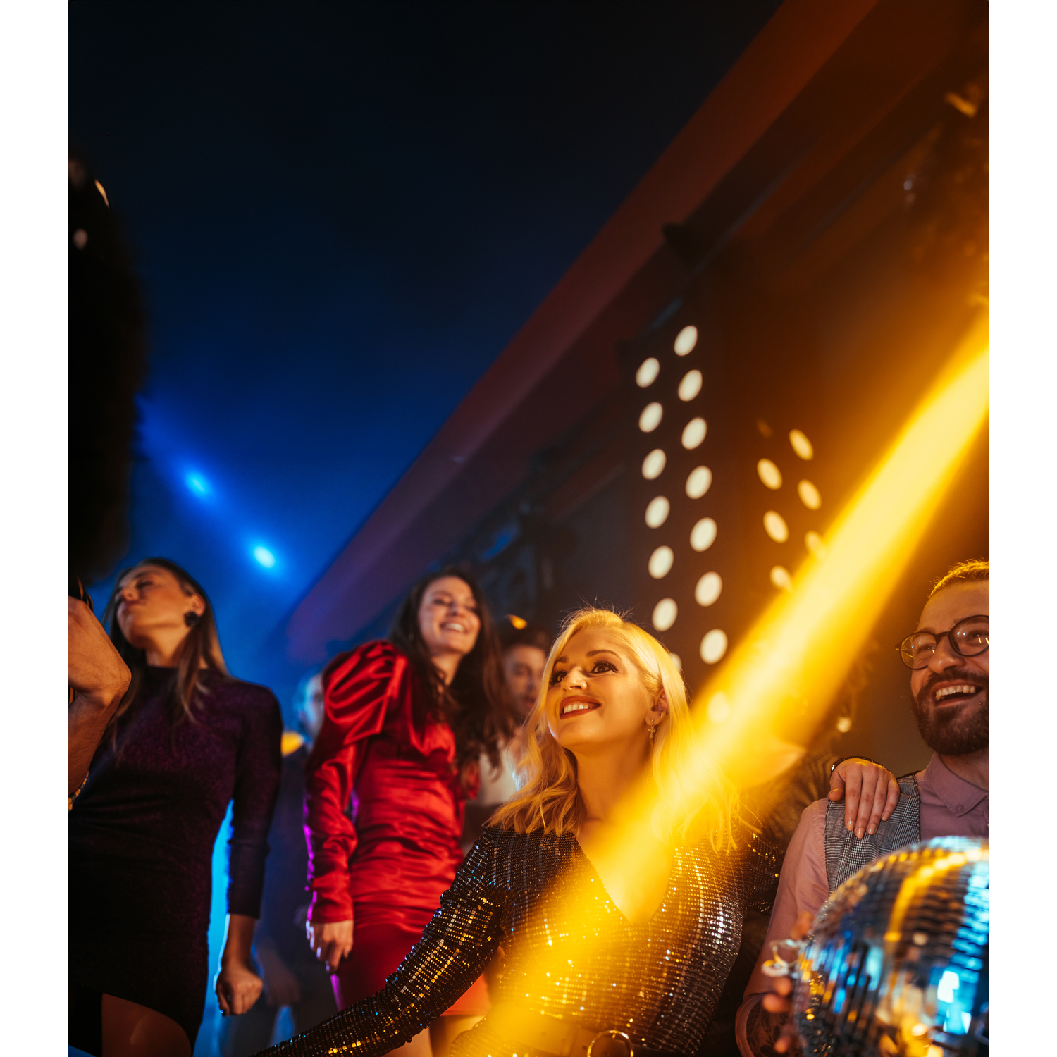 Een groep mensen die dansen in een nachtclub, een discobal reflecteert licht.