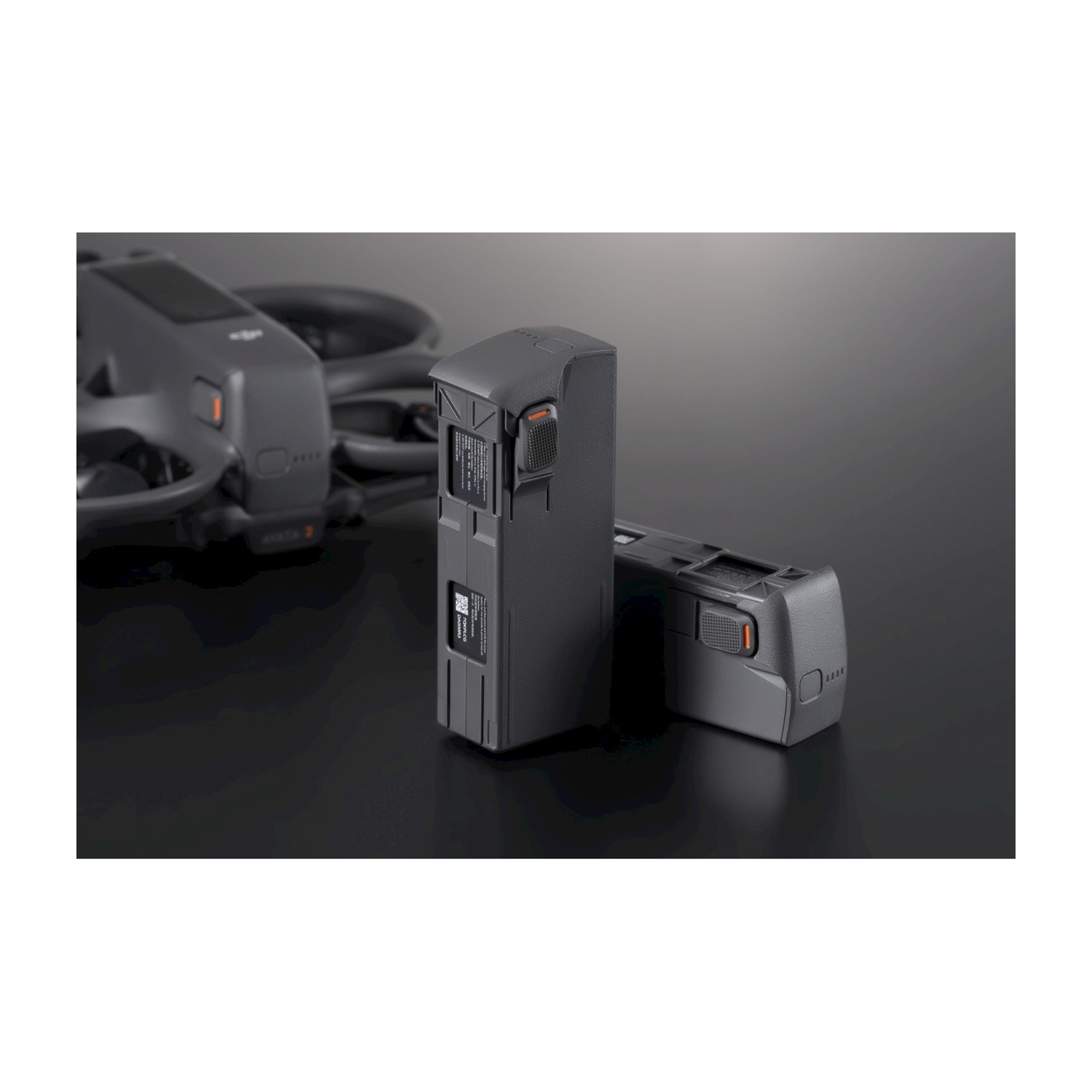 Due batterie per drone su una superficie nera. Drone grigio sullo sfondo.