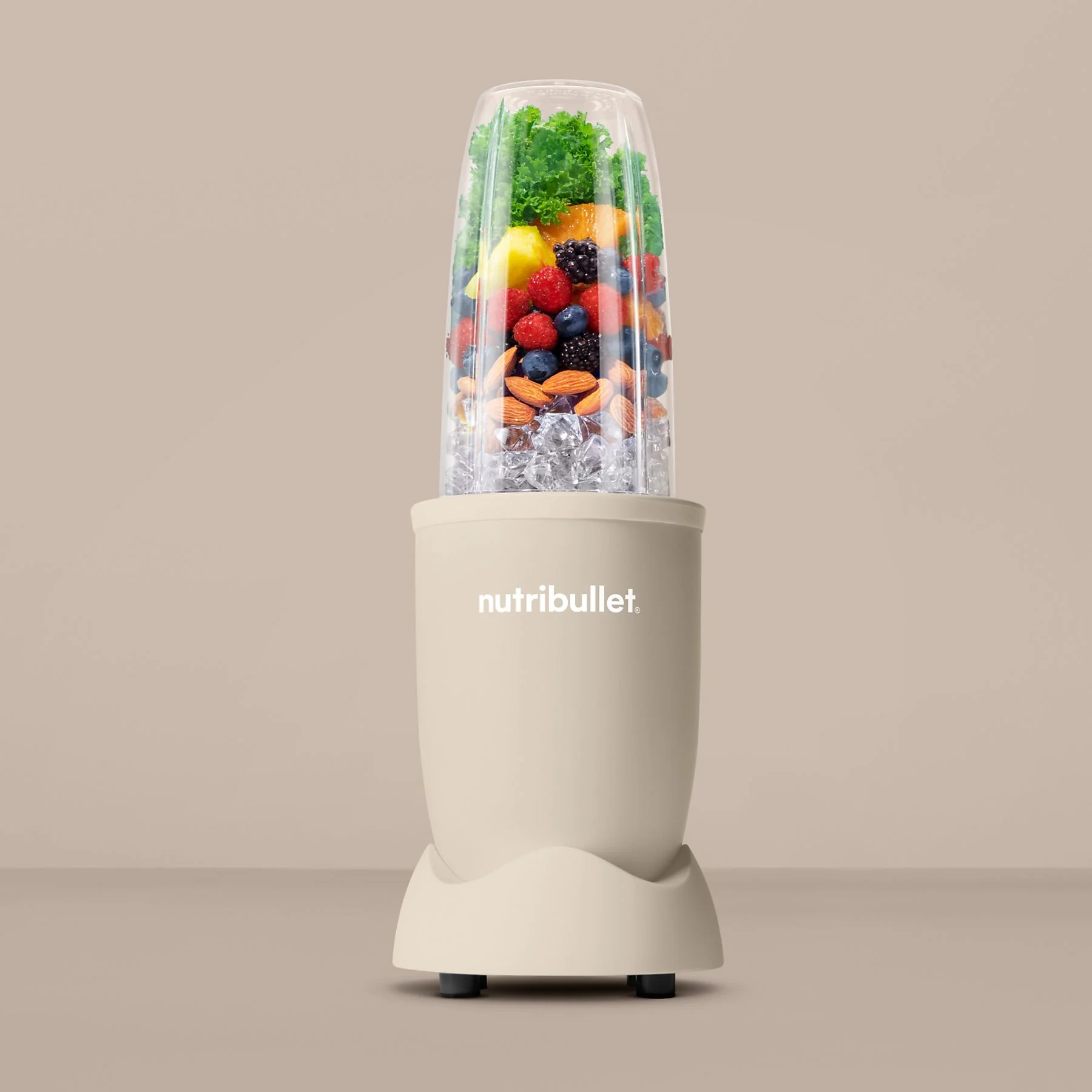 Un blender Nutribullet beige rempli de fruits et de glace.