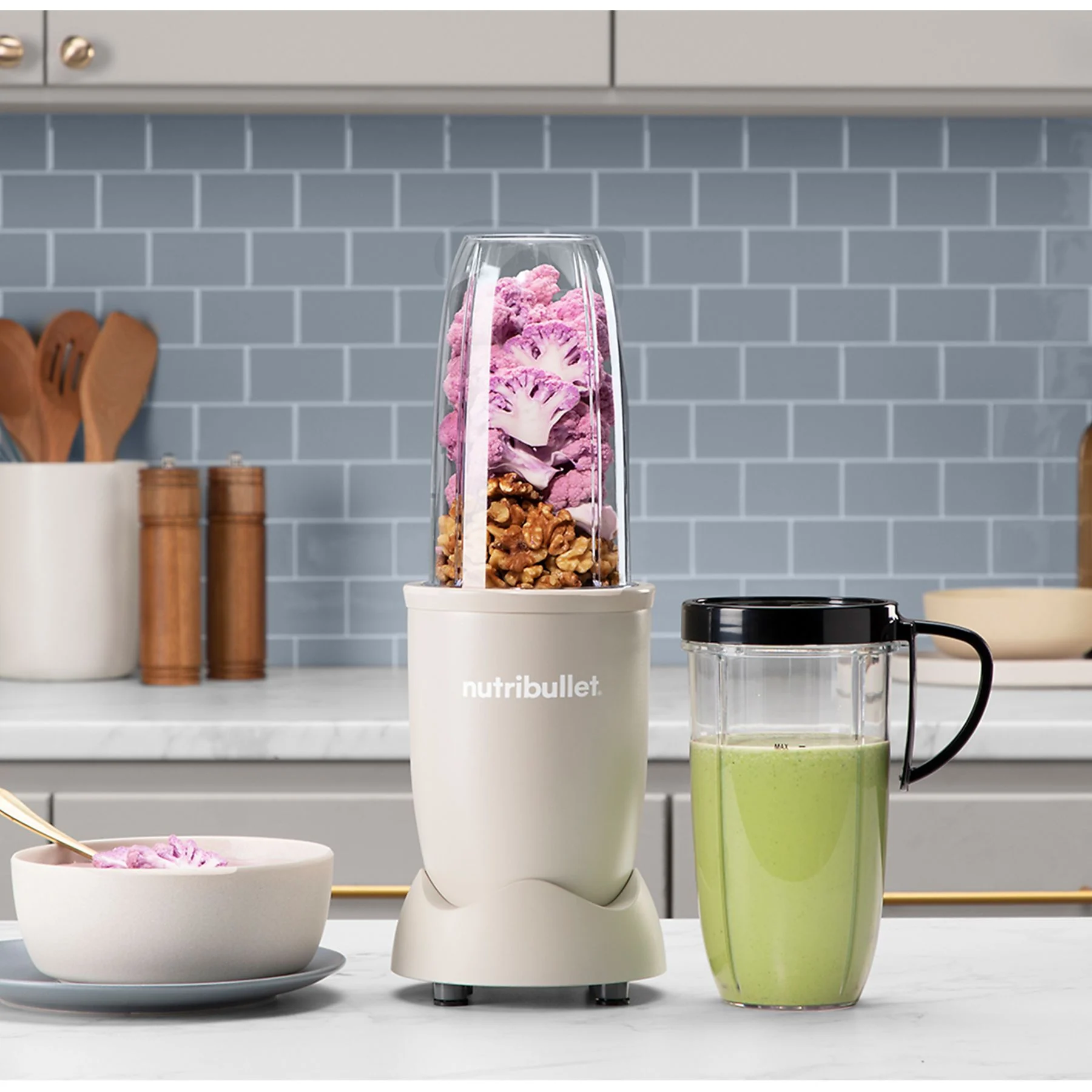 Mixeur avec ingrédients. Contient du chou-fleur violet, des noix et un smoothie vert.