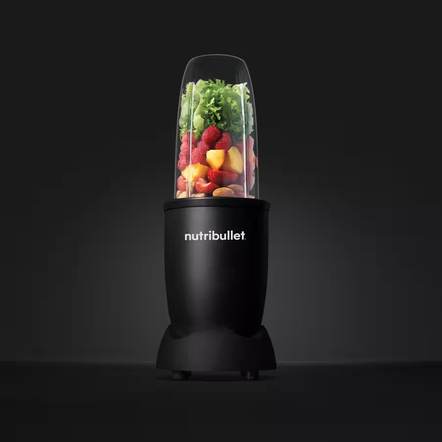 Un mélangeur Nutribullet noir avec des fruits et des légumes verts à l'intérieur d'une tasse transparente.
