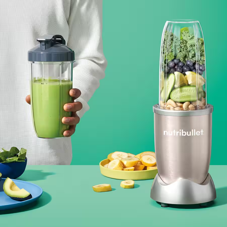 NutriBullet-Mixer mit Zutaten. Eine Person hält einen Smoothie-Becher.