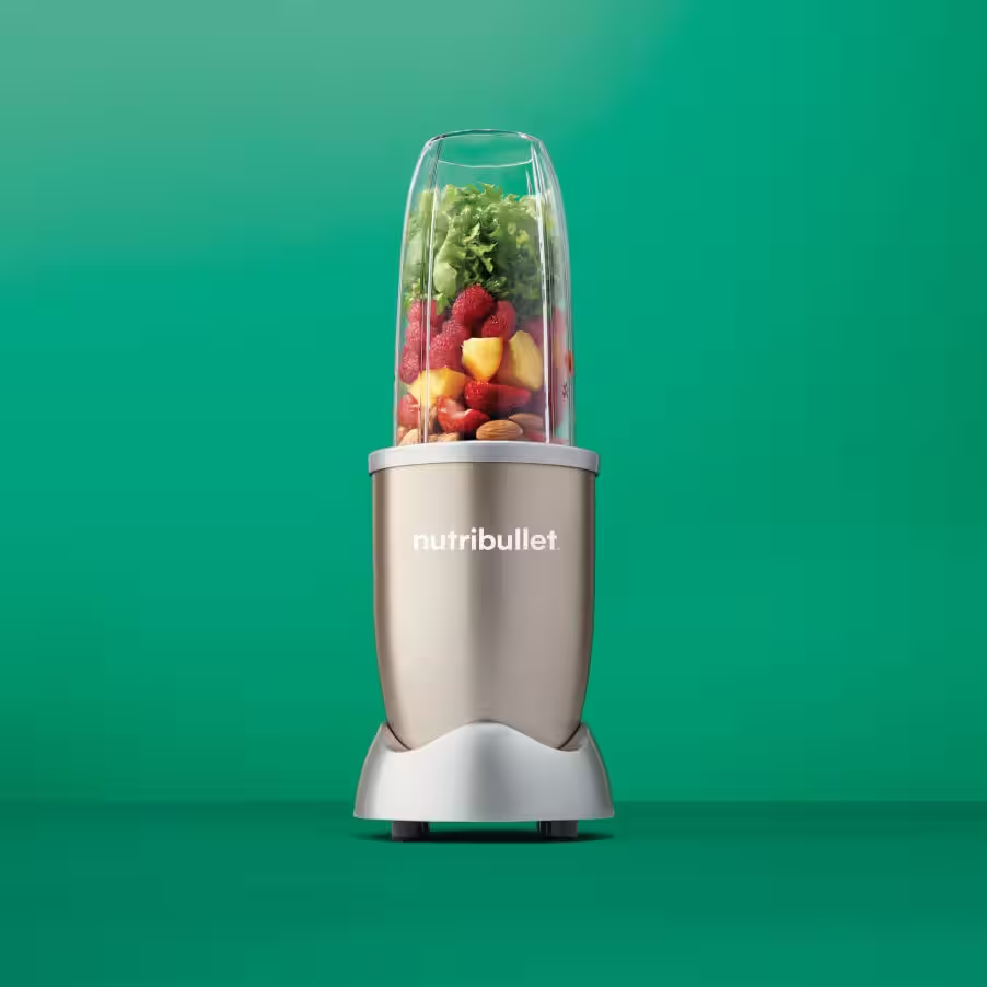 Ein Mixer gefüllt mit Früchten und Grünzeug. Der Mixer steht auf einem hellen Sockel, grüner Hintergrund.