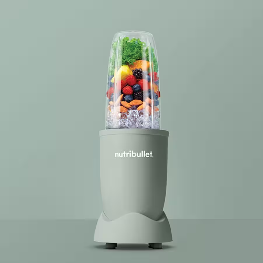 Ein Mixer mit Früchten, Eis und einem grünen Sockel.