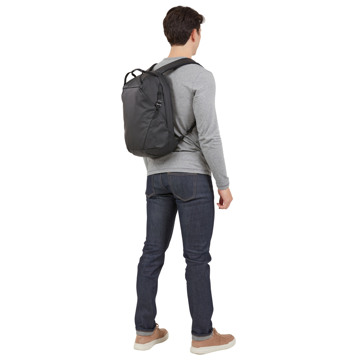 Un homme avec un sac à dos, vu de dos, debout sur fond blanc.