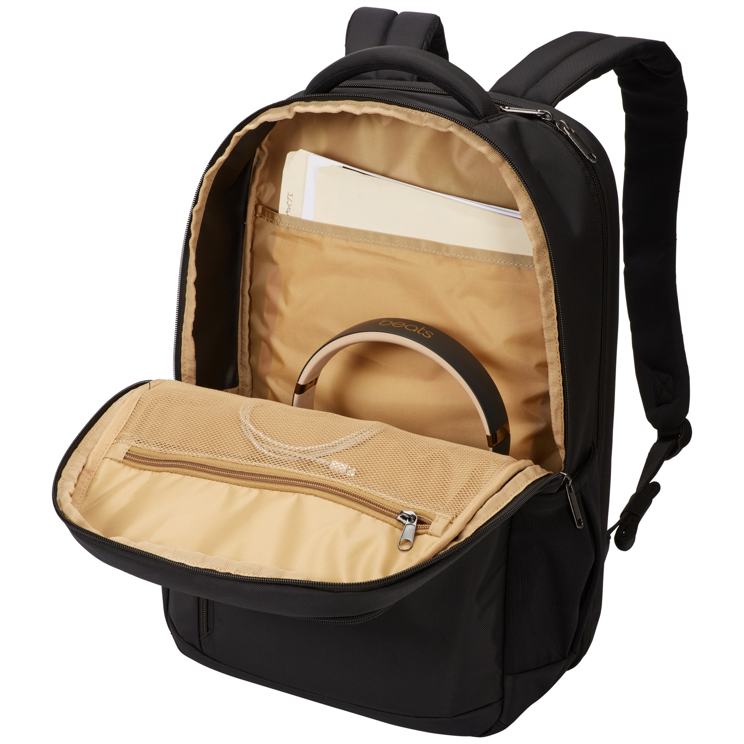 Sac à dos noir avec compartiments ouverts. Contient un carnet et un casque. Fond blanc.
