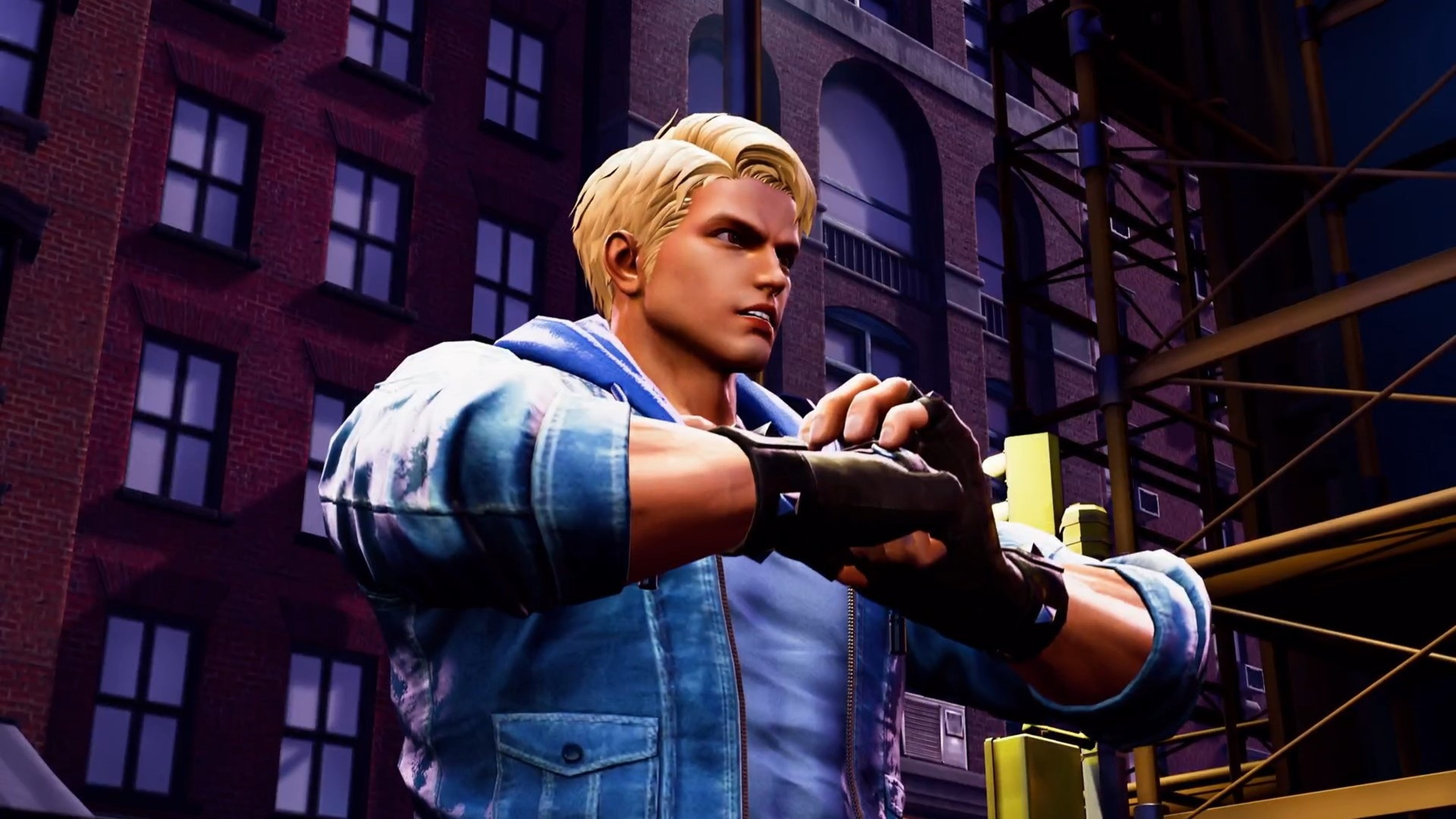 Ein Mann in einer blauen Jacke und blonden Haaren blickt zur Seite. Im Hintergrund ein Backsteingebäude, rechts ein Gerüst.