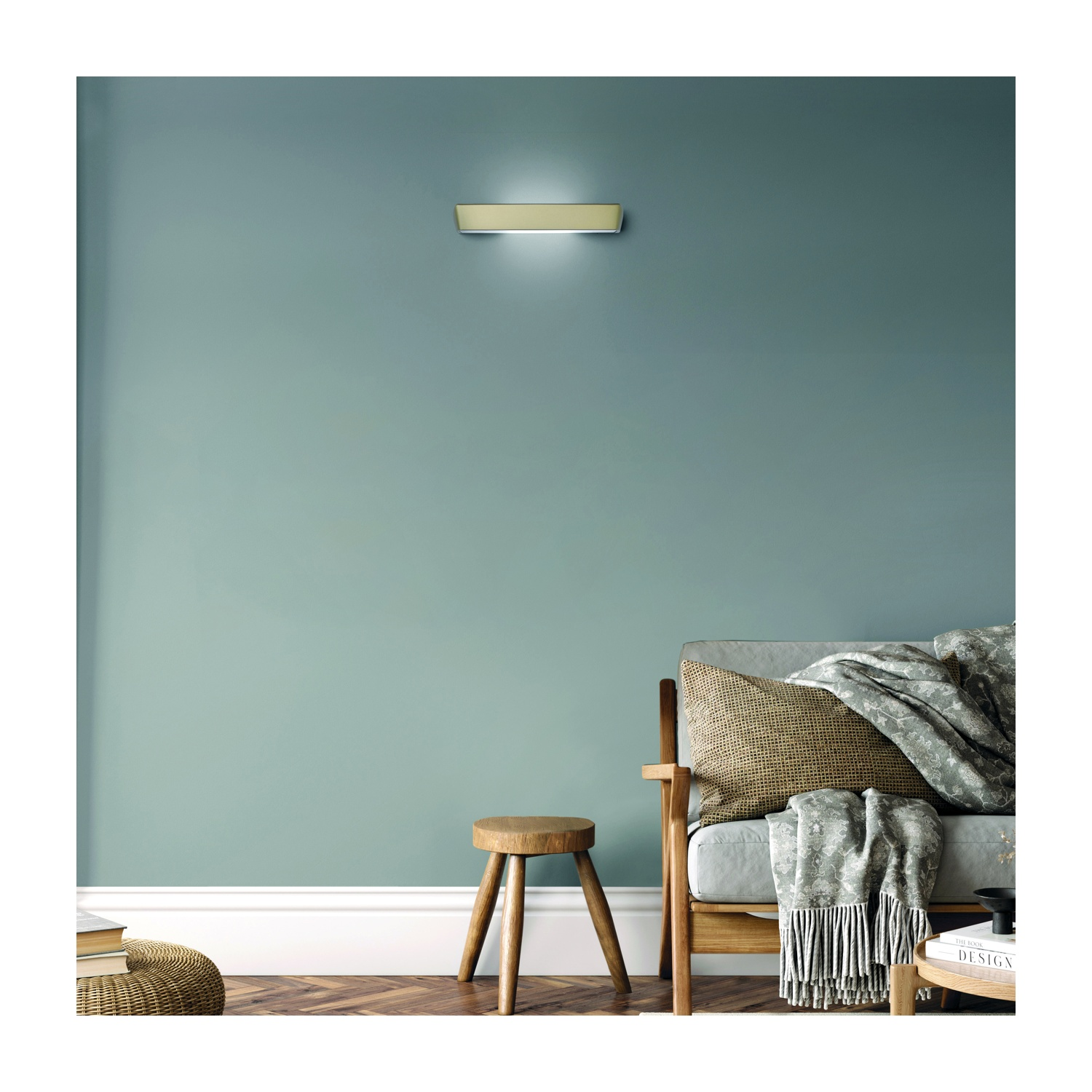 Una stanza con una luce sulla parete. Un divano, uno sgabello, una coperta e dei libri sono sulla scena.
