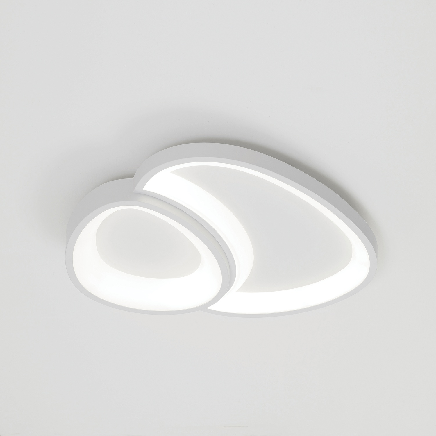 Una plafoniera bianca, di forma ovale, con due sezioni luminose collegate, contro un soffitto bianco.