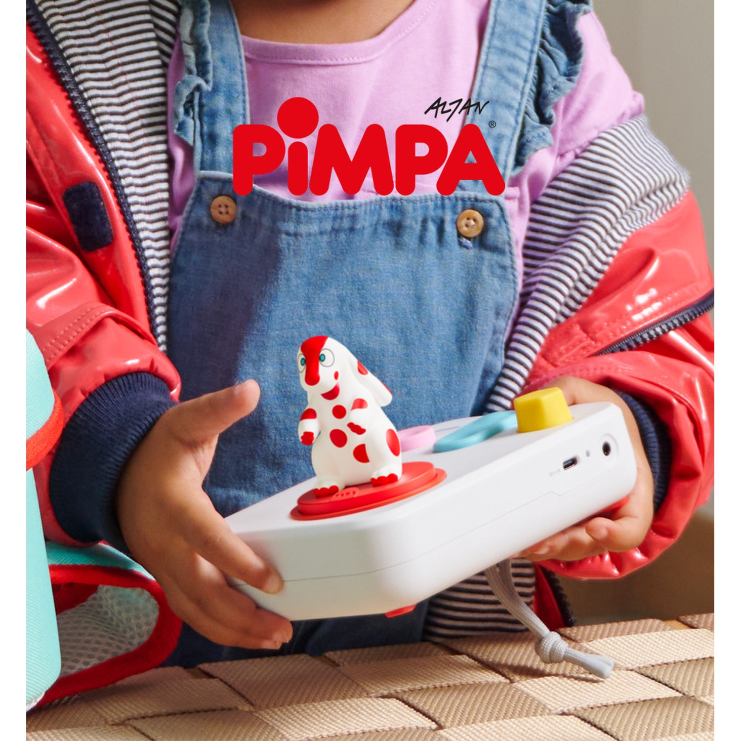 Bambino che tiene un giocattolo bianco con una figura di cane rosso e bianco. Il giocattolo ha pulsanti e un logo.