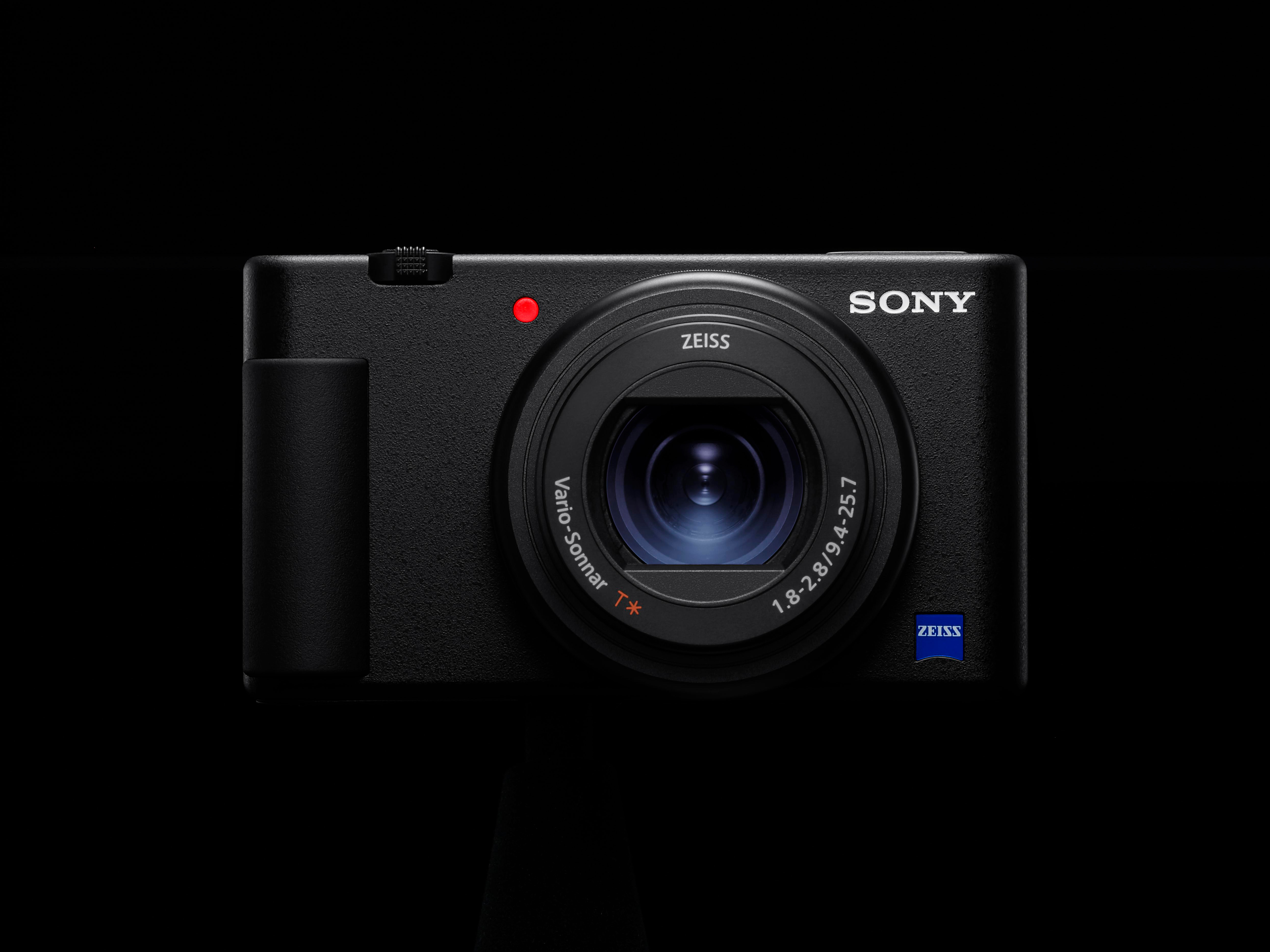 Schwarze Sony-Kamera mit Objektiv und rotem Punkt, zentriert auf schwarzem Hintergrund.