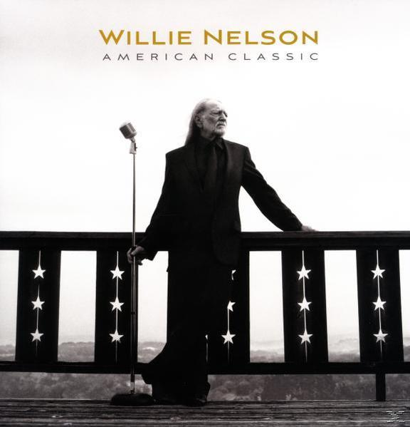 Willie Nelson mikrofonnal a verandán, fekete öltönyben, hosszú hajjal. A háttérben korlát és tájkép látható.