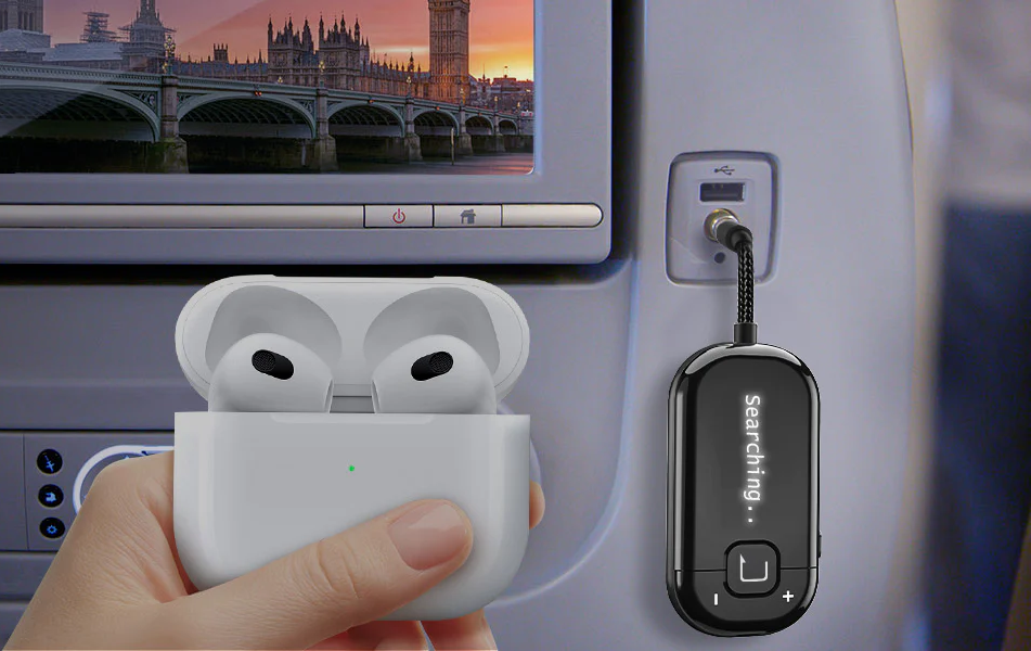 Main tenant un étui AirPods et un appareil noir branché sur un écran d'avion.