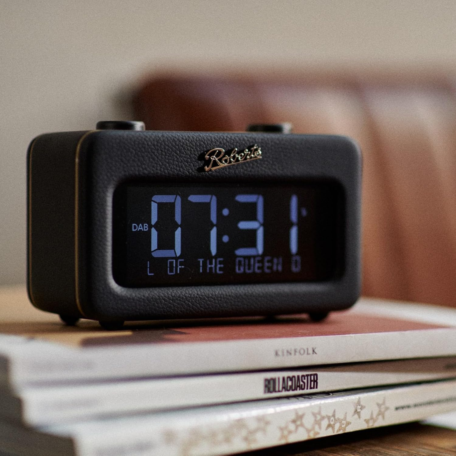Horloge noire avec affichage numérique. L'heure est 07h31. L'horloge est sur une pile de livres.