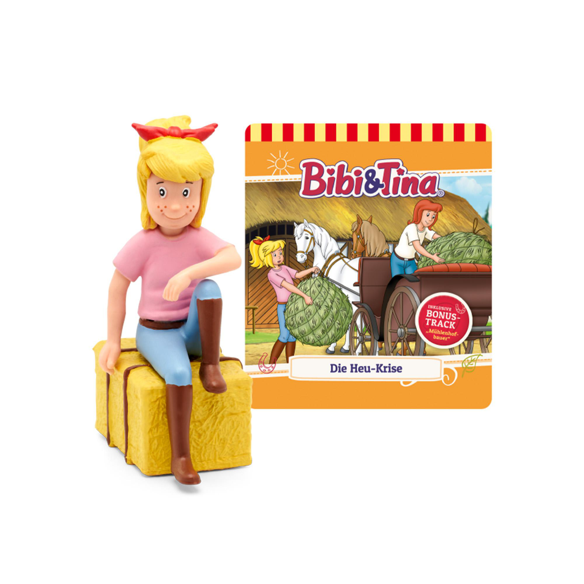 Eine Figur eines Mädchens und ein Buchcover mit einem Mädchen auf einem Wagen mit Heu und Pferden.