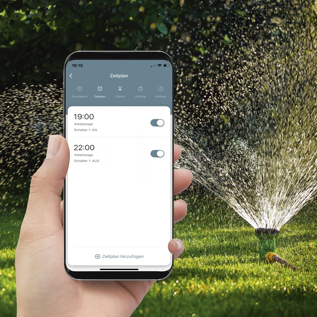 Person hält Smartphone mit Gartenbewässerungsplan auf Rasen.