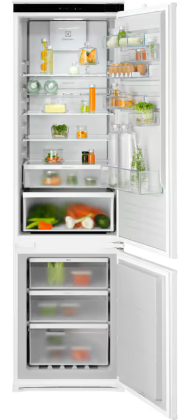 Biała lodówka z otwartymi drzwiami. Półki wypełnione są produktami spożywczymi, szuflady zawierają warzywa i owoce.