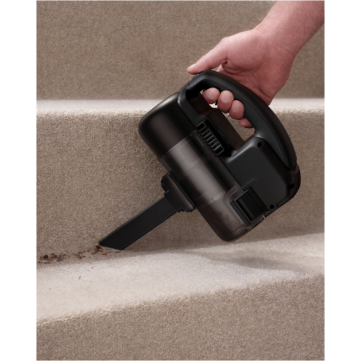 A hand vacuuming a carpeted staircase. The vacuum is black.