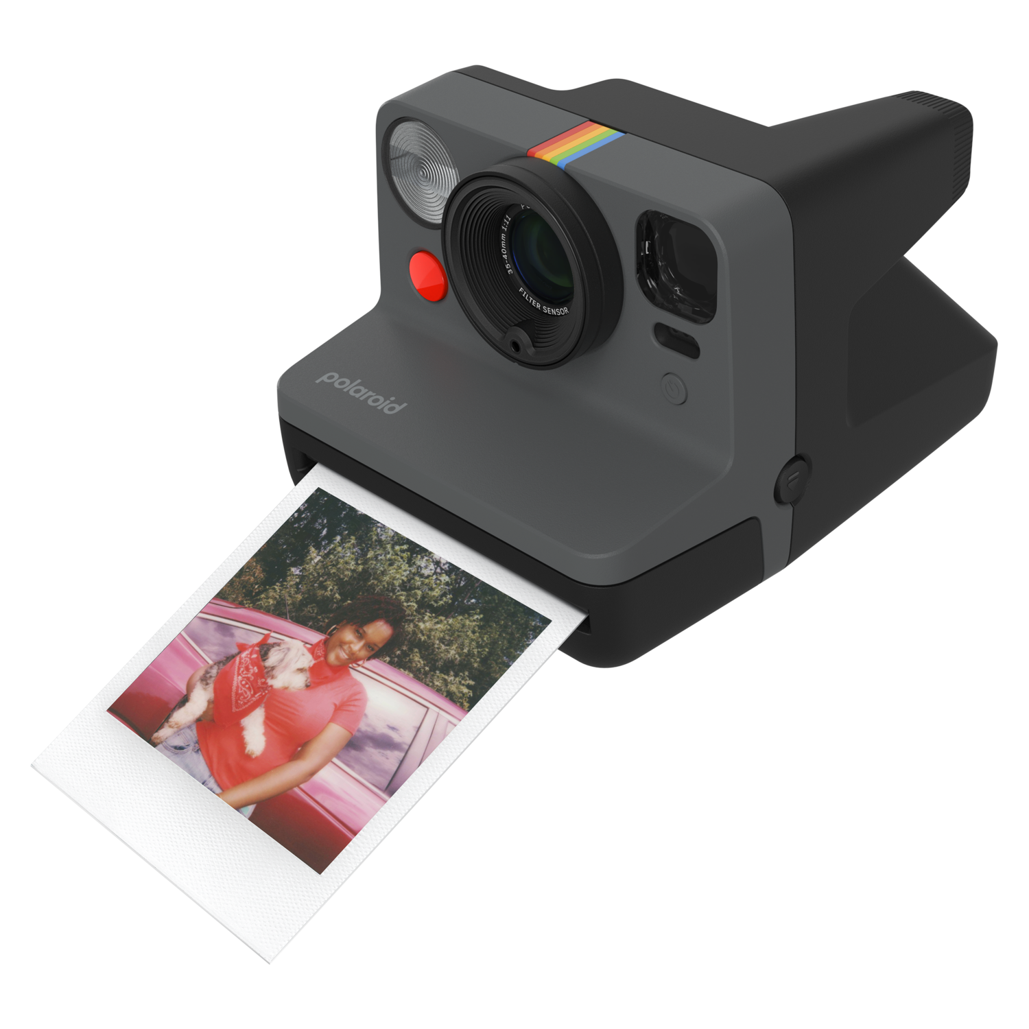 A Polaroid camera with a photo, showing a person holding a dog, in a red car.