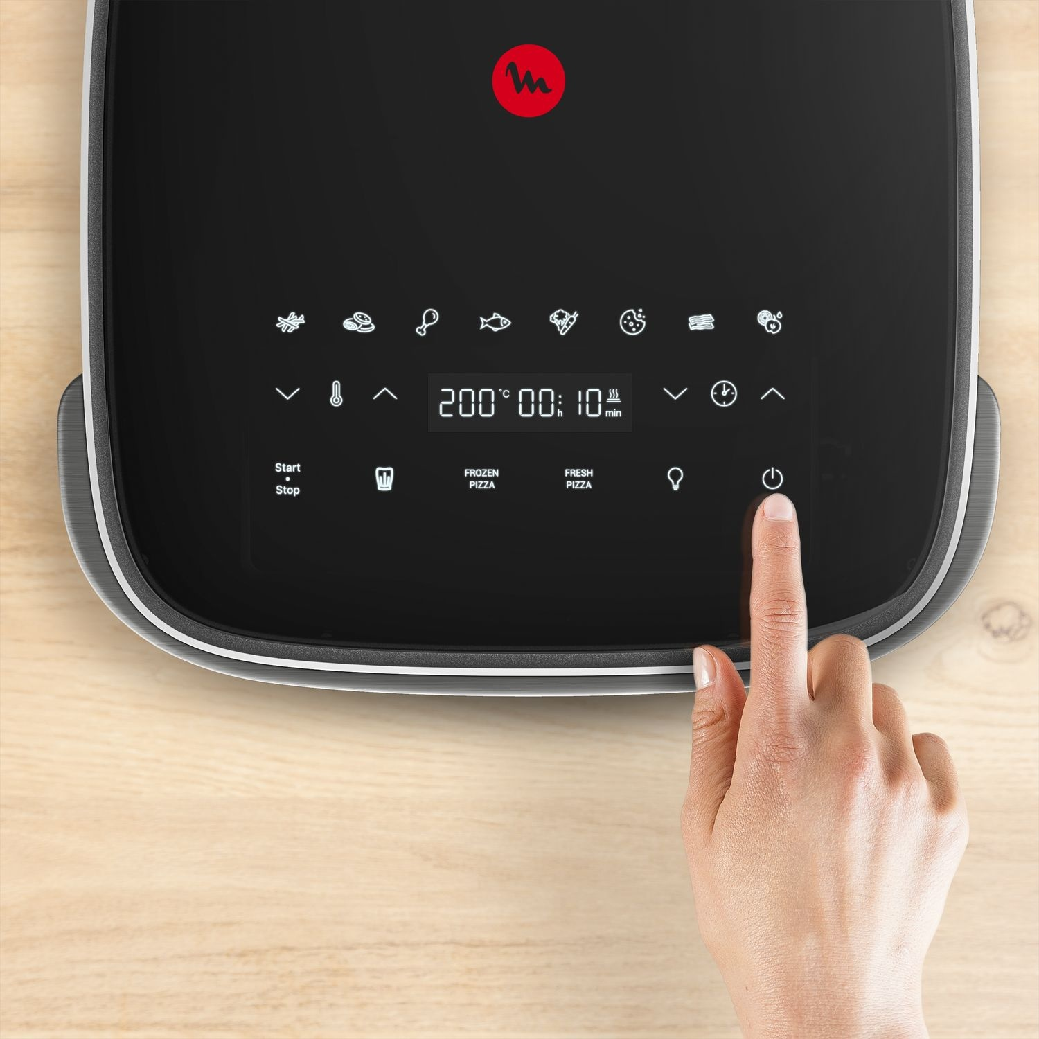 A hand presses the power button on a black air fryer. The display shows 200 degrees, 00:10 minutes, and various cooking icons.