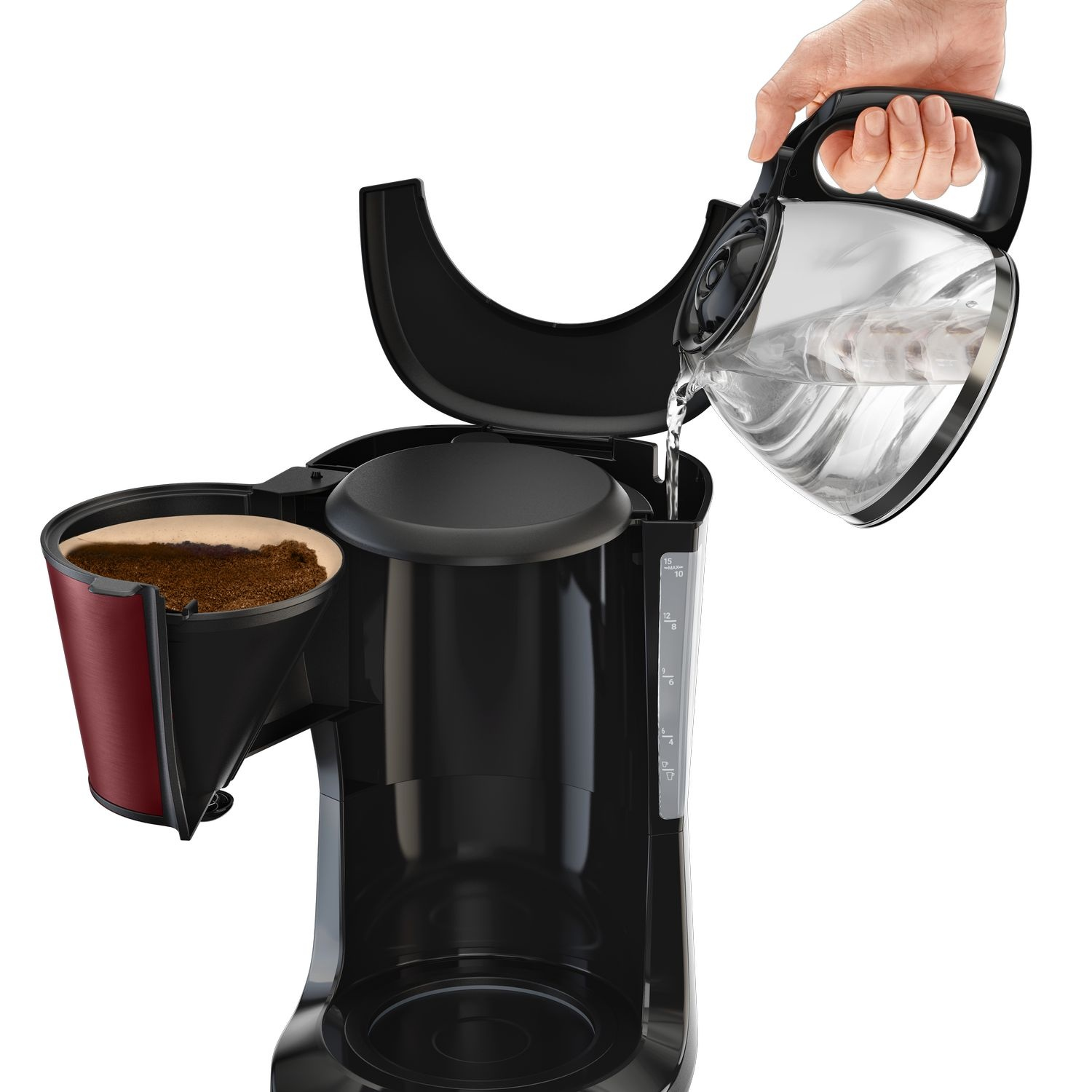 A hand pours water from a carafe into a coffee maker with a coffee filter.