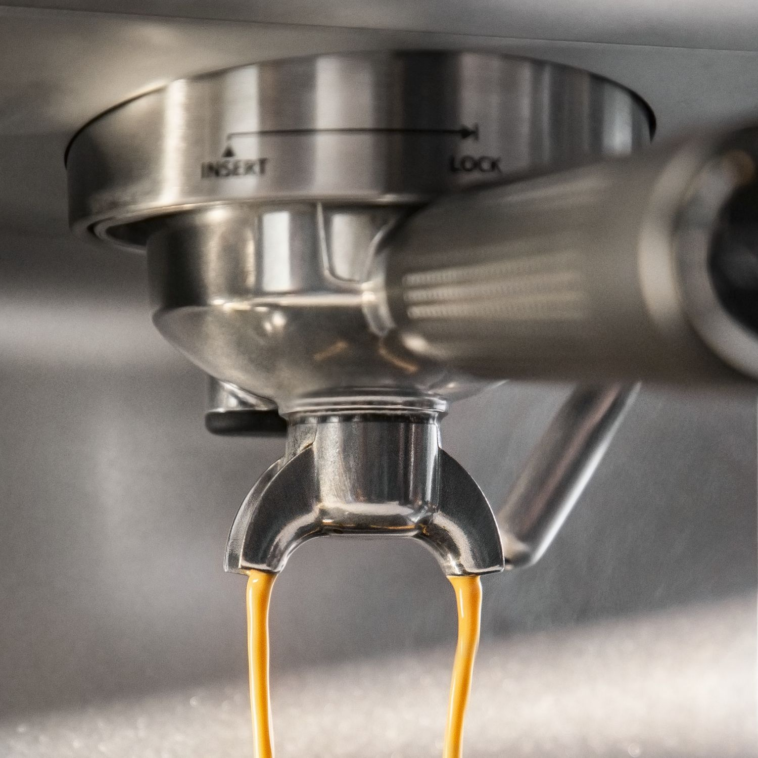 Gros plan sur une machine à expresso. Le café coule d'un bec. La machine est en métal brillant.
