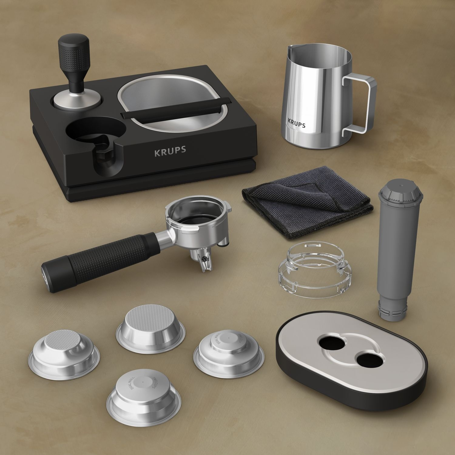 Accessoires de cafetière : tamper, porte-filtre, paniers filtrants, pichet à lait, chiffon de nettoyage et autres pièces sur une table.