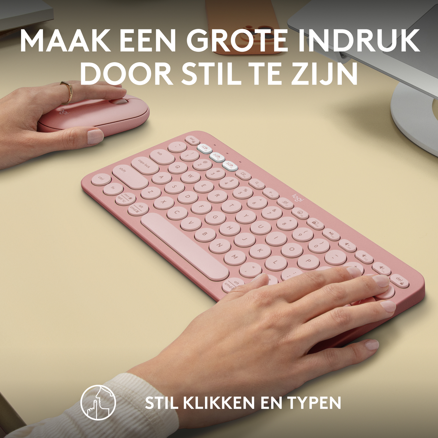 Roze toetsenbord en muis op een bureau. Handen zijn in de buurt. Tekst op de afbeelding, in het Nederlands.