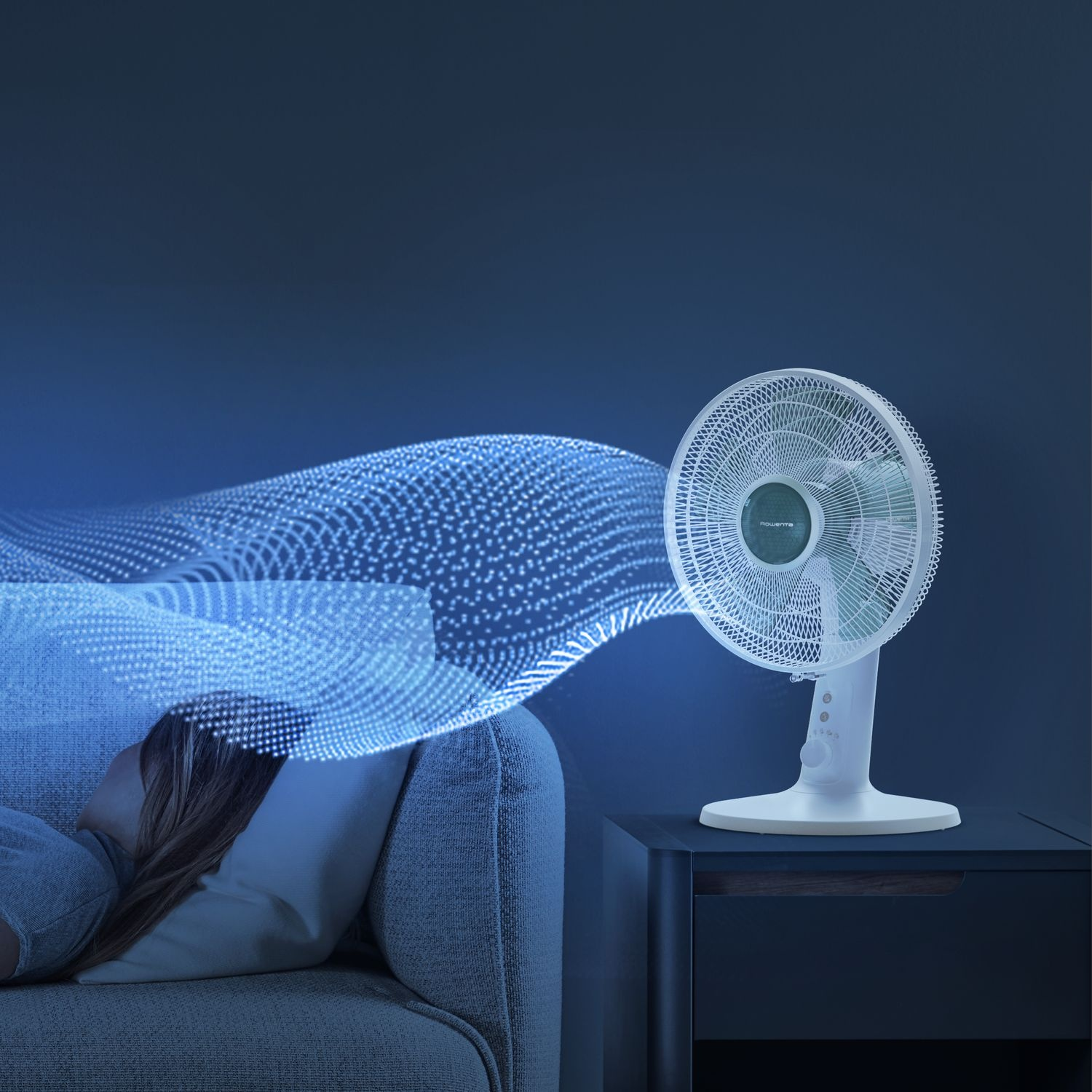 White fan blowing air, a person sleeping on the couch. Blue background.
