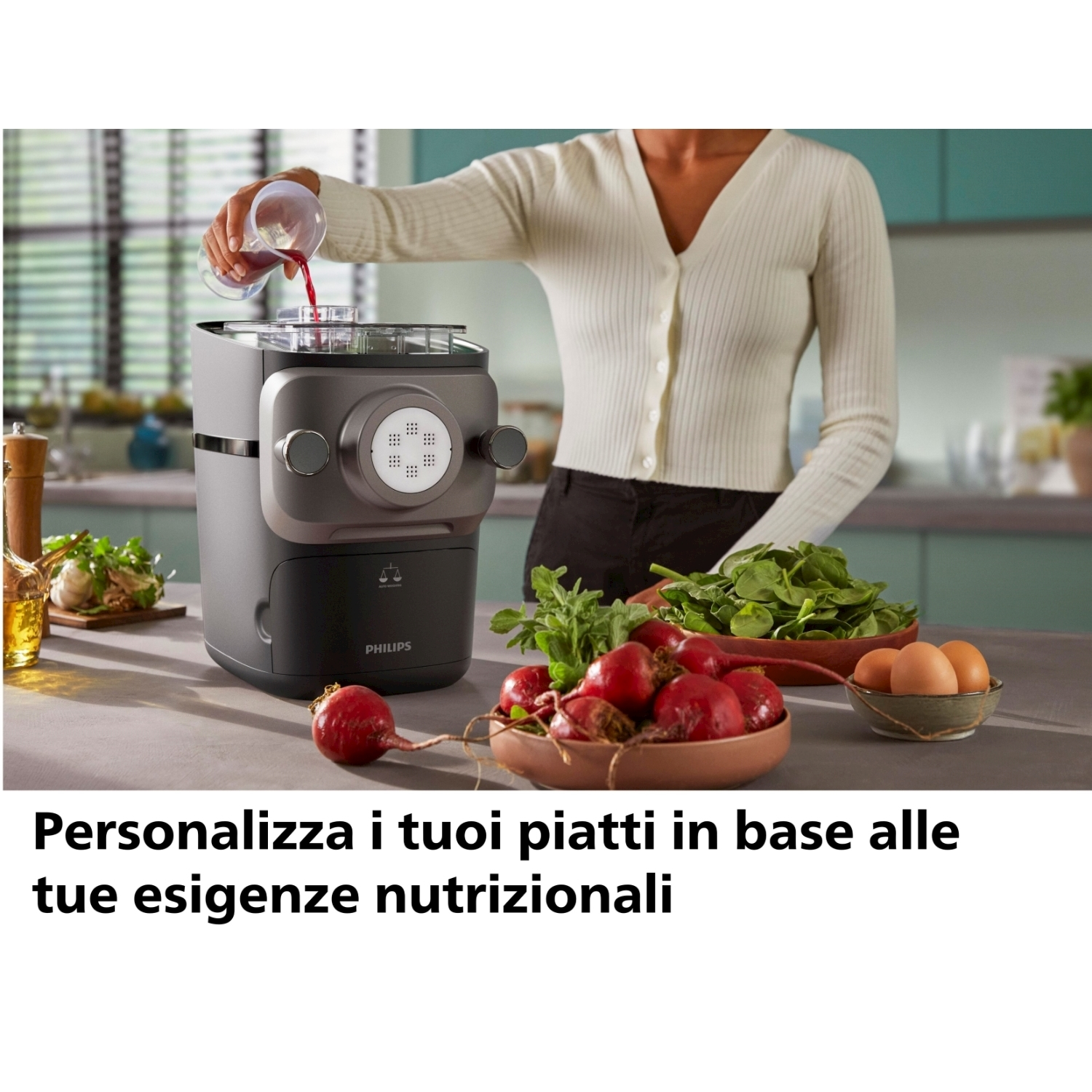 Una persona aggiunge liquido a una macchina per la pasta Philips, con ingredienti come barbabietole e uova in vista.
